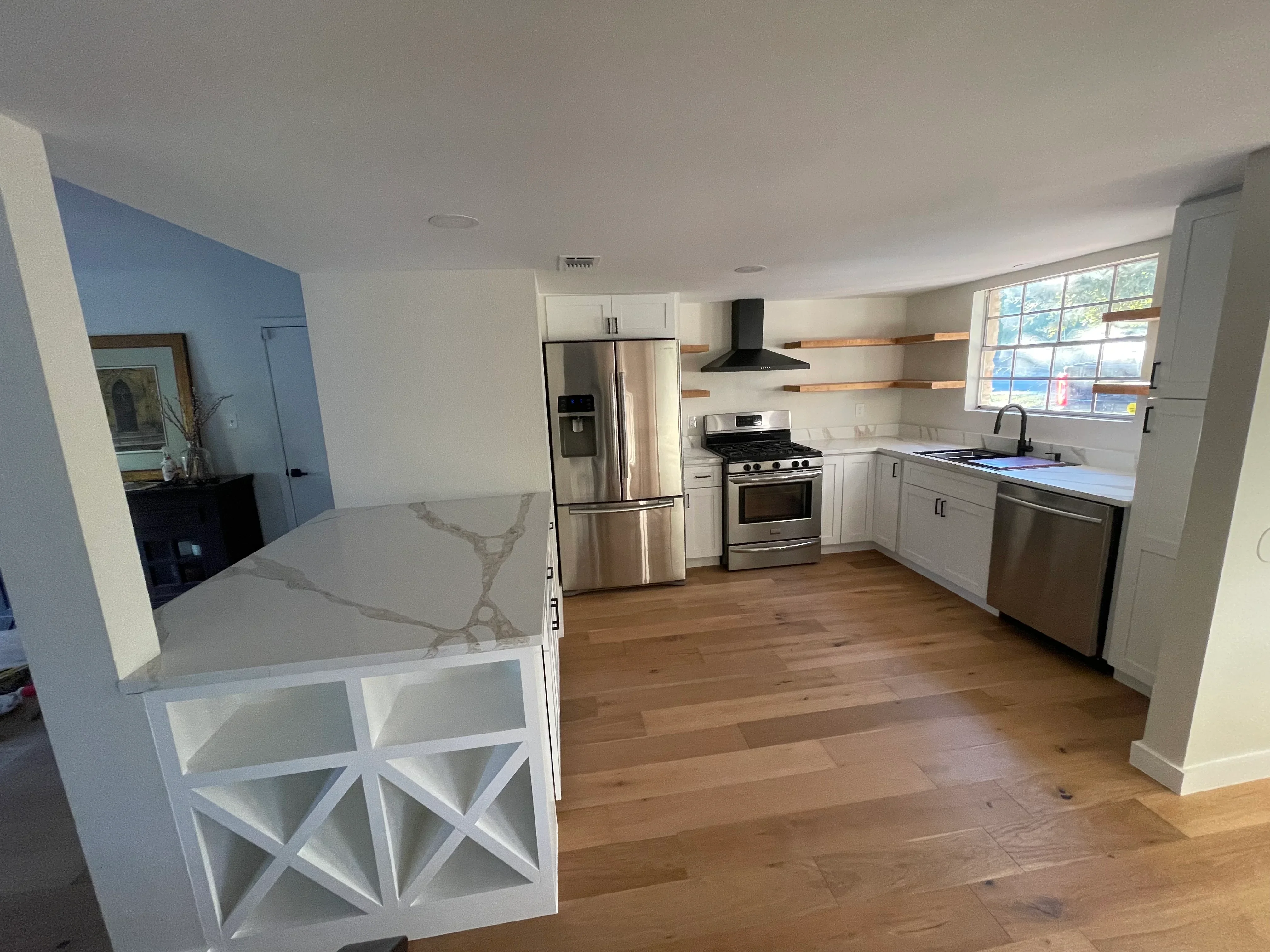 Modern kitchen with white cabinetry, quartz counters, stainless steel appliances, and hardwood flooring