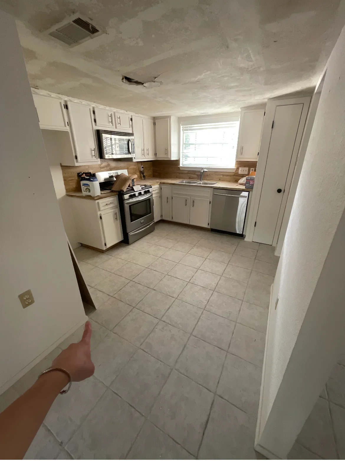 Kitchen with white cabinets, ceramic tile flooring, drywall ceiling repair, and stainless steel appliances