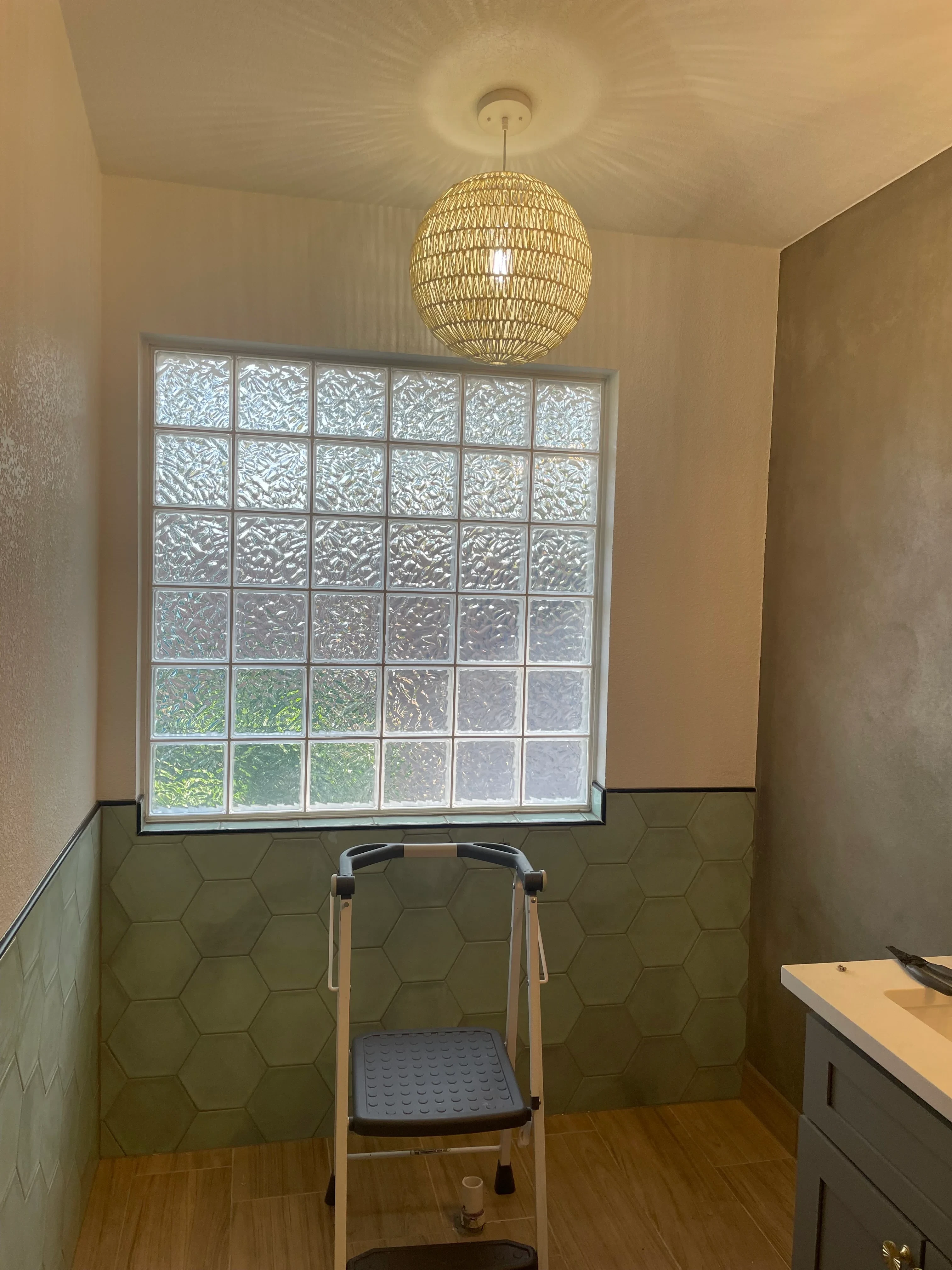 Bathroom with glass block window, hexagonal tile wall, and woven pendant light fixture