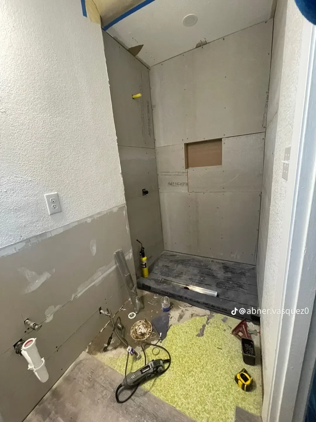 Bathroom under renovation with drywall installation, framing, and plumbing rough-in for shower