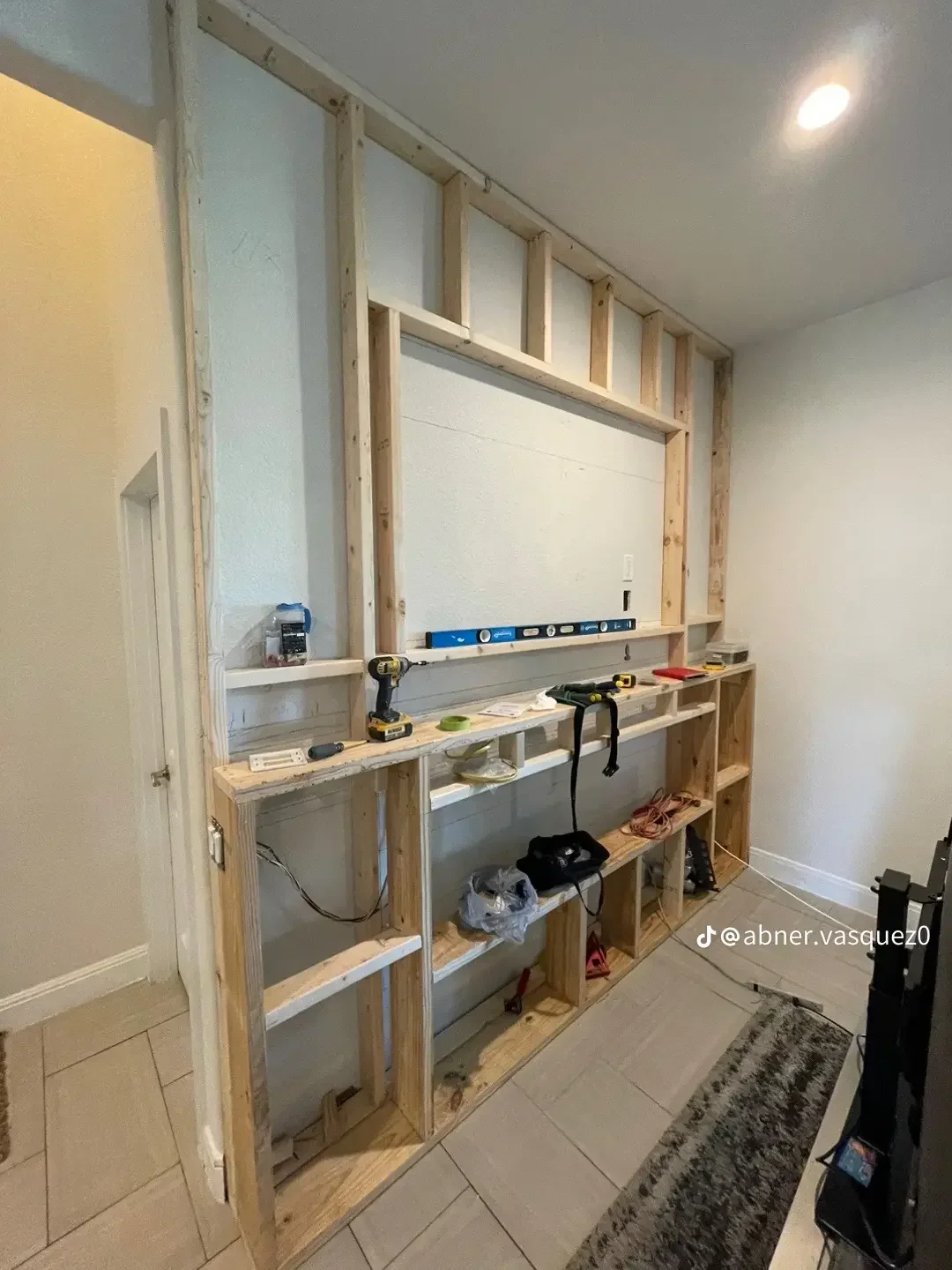 Custom built-in shelving with wood framing, drywall backing, and multi-level storage cabinetry during installation