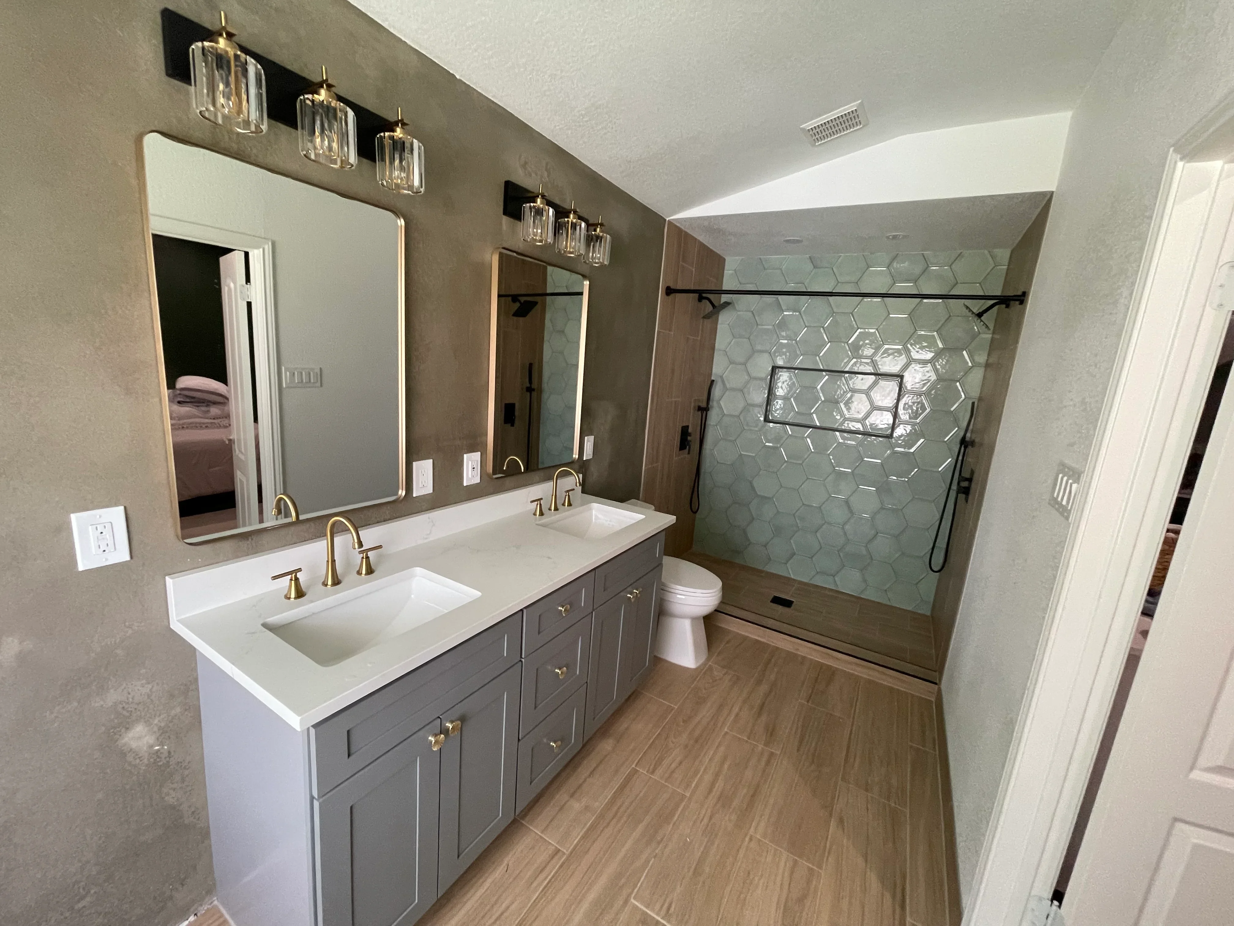 Modern bathroom with gray vanity, quartz countertop, hexagonal tile shower, and wood-look flooring