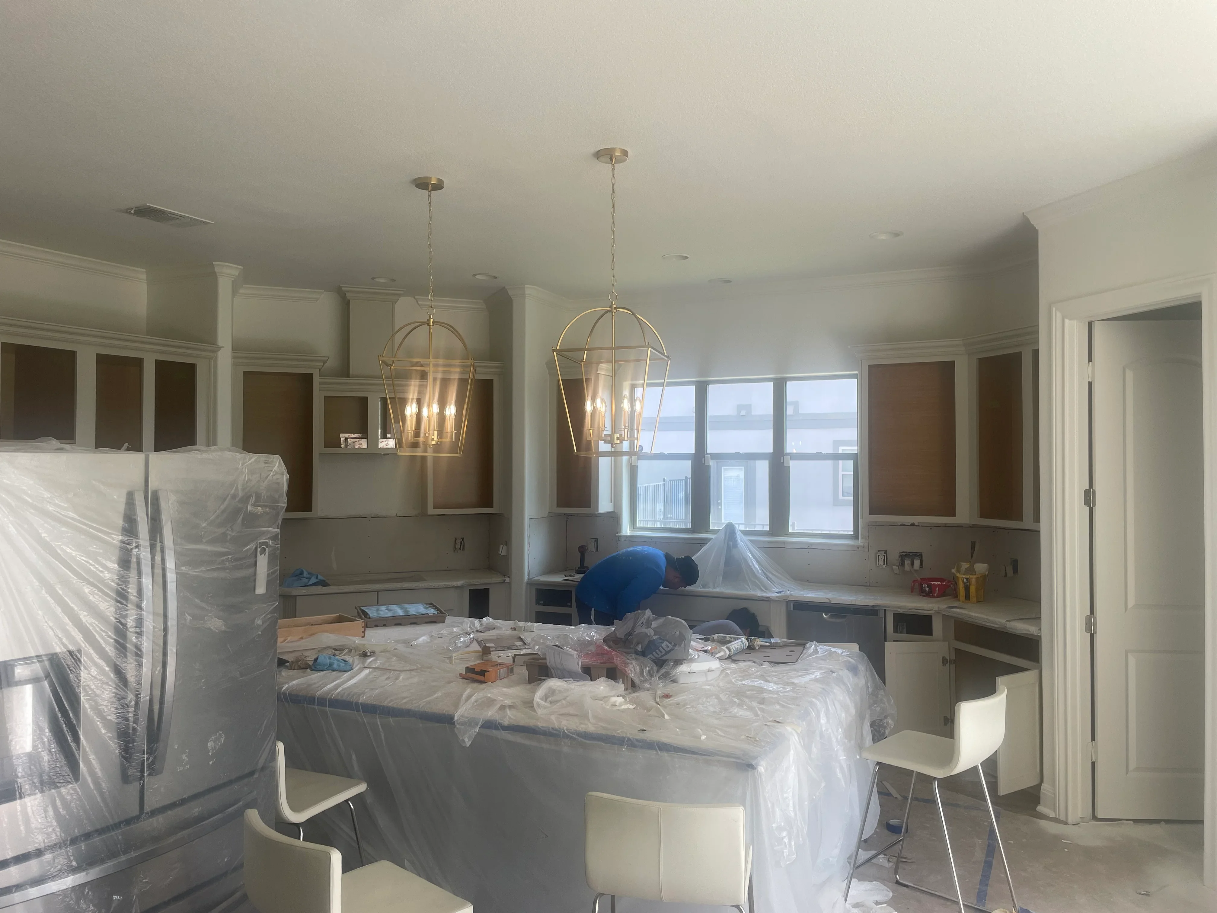 Kitchen remodel with white cabinetry, pendant lights, and granite countertops under construction