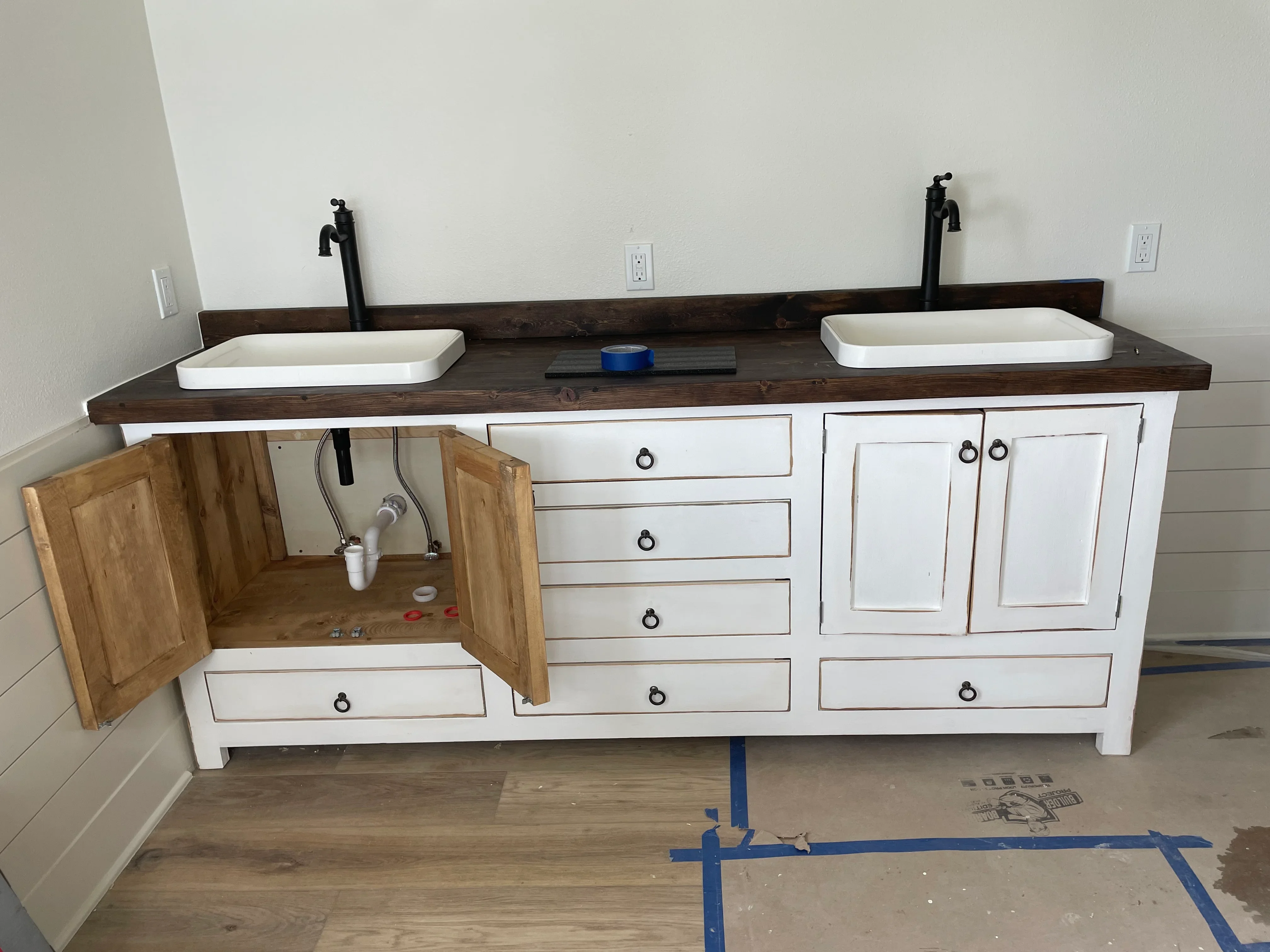 Dual white vanity with dark wood countertop, vessel sinks, and black faucets in bathroom