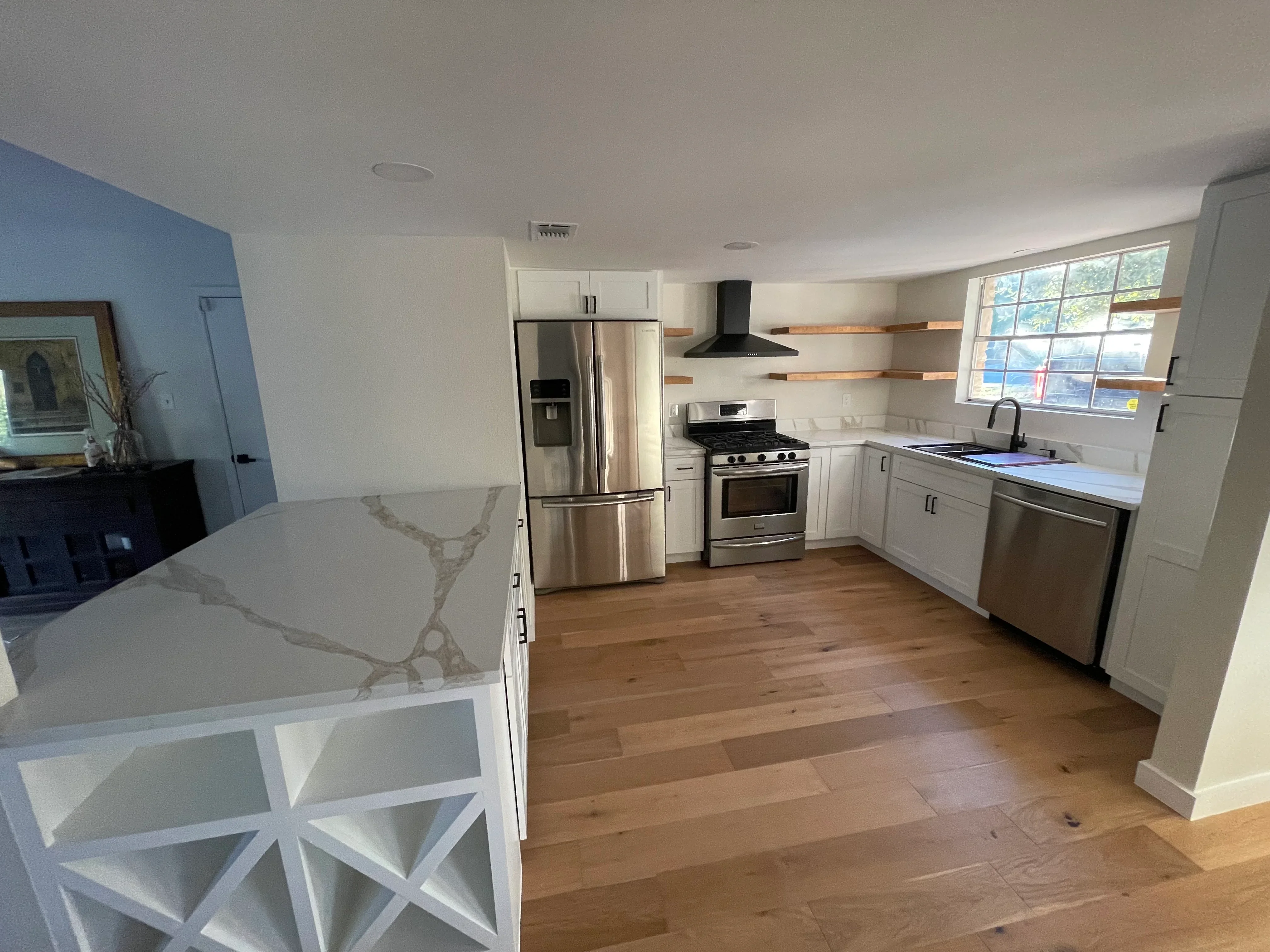 Modern kitchen with white cabinetry, quartz counters, stainless steel appliances, and hardwood flooring