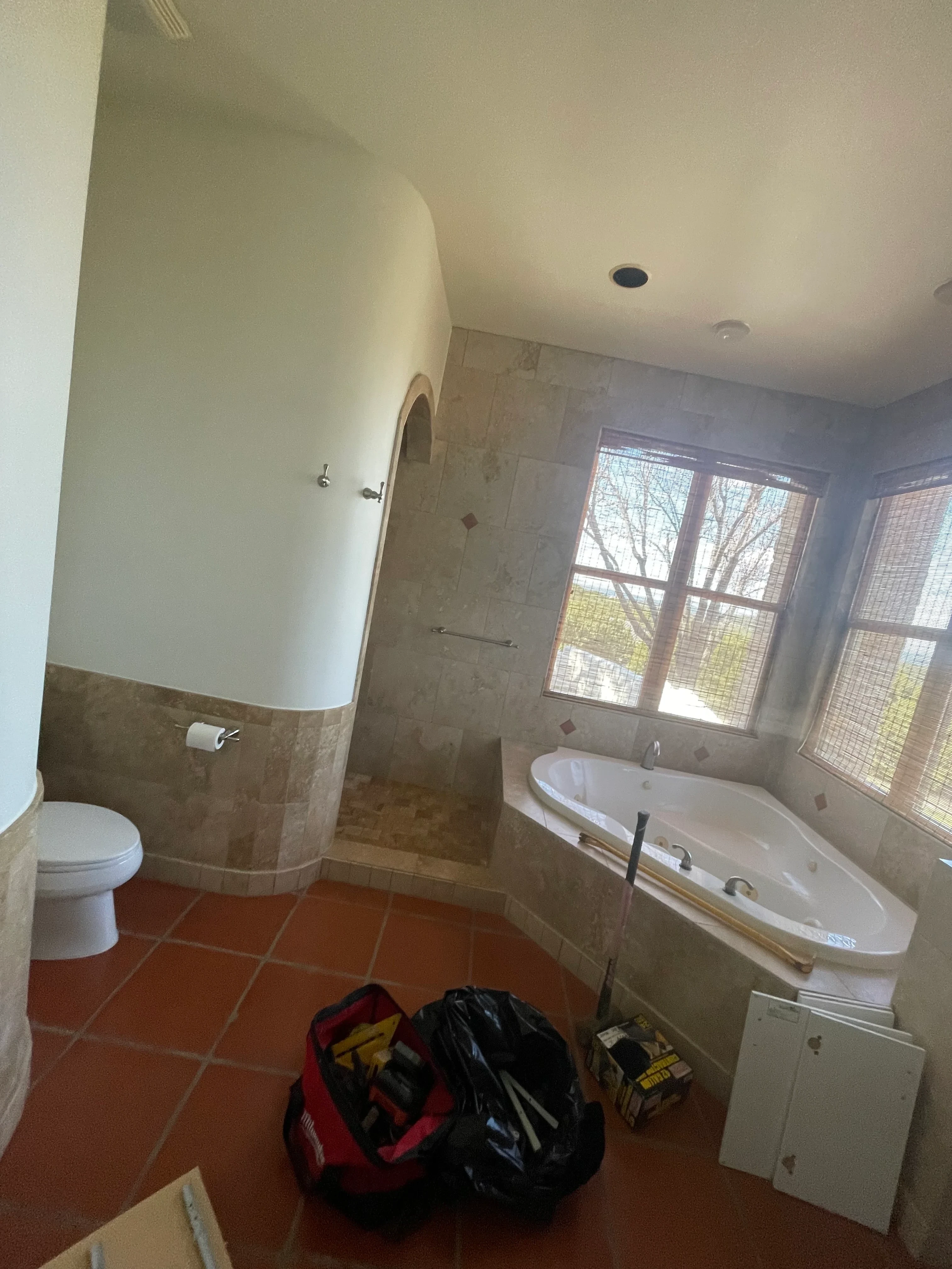 Bathroom with new ceramic tile flooring, updated wall tile, white bathtub, and skylight window
