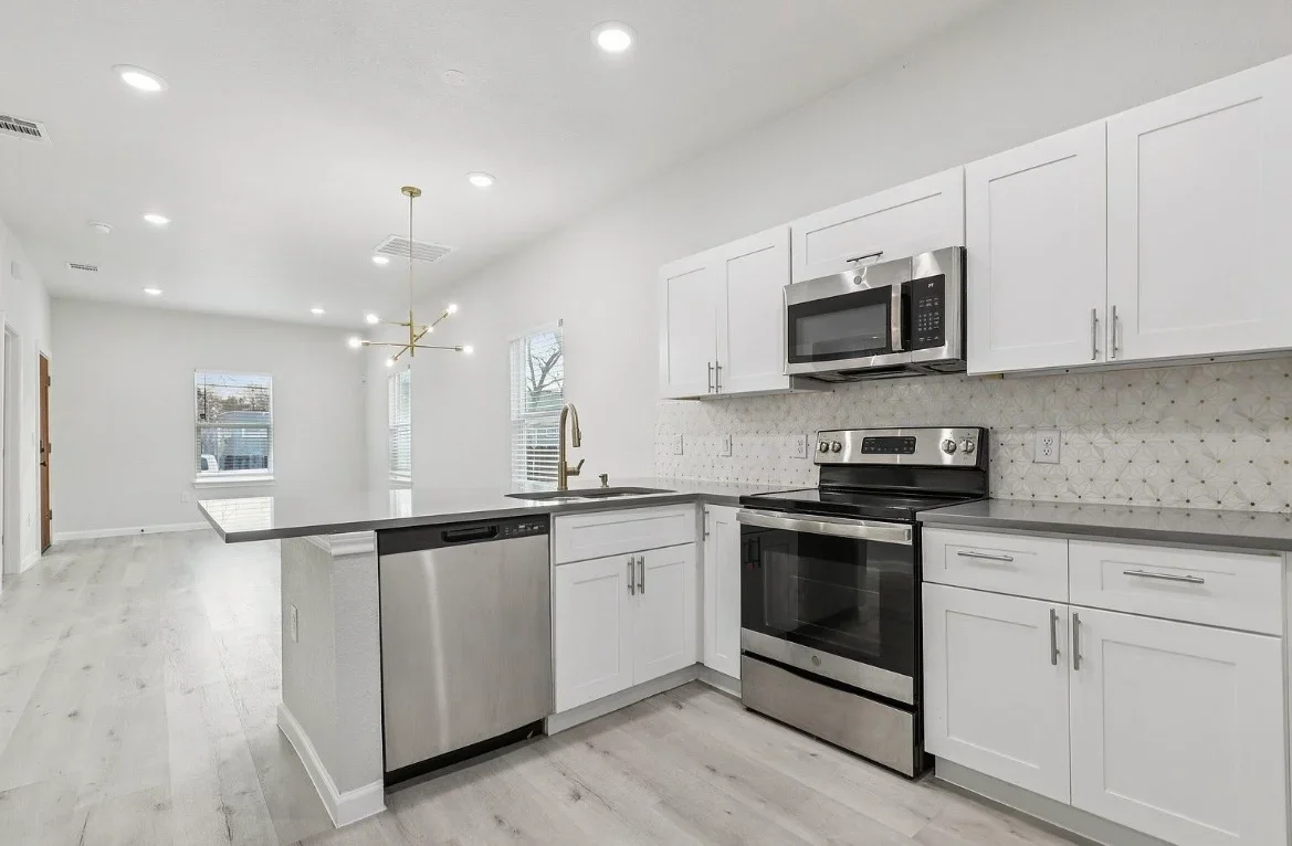 White kitchen cabinets, black quartz counters, stainless steel appliances, island with seating