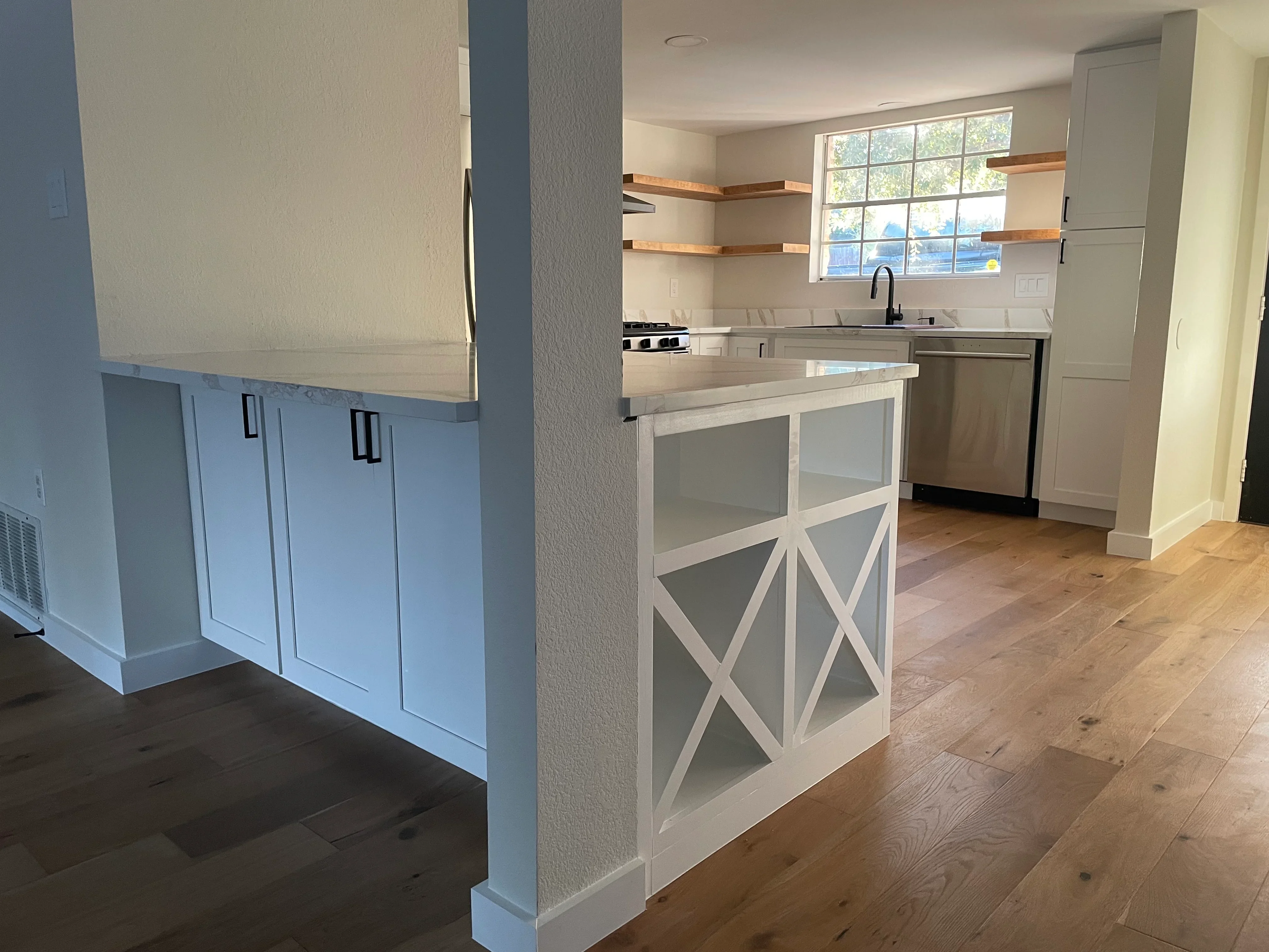 Modern kitchen with white cabinetry, island, stainless steel appliances, and hardwood flooring