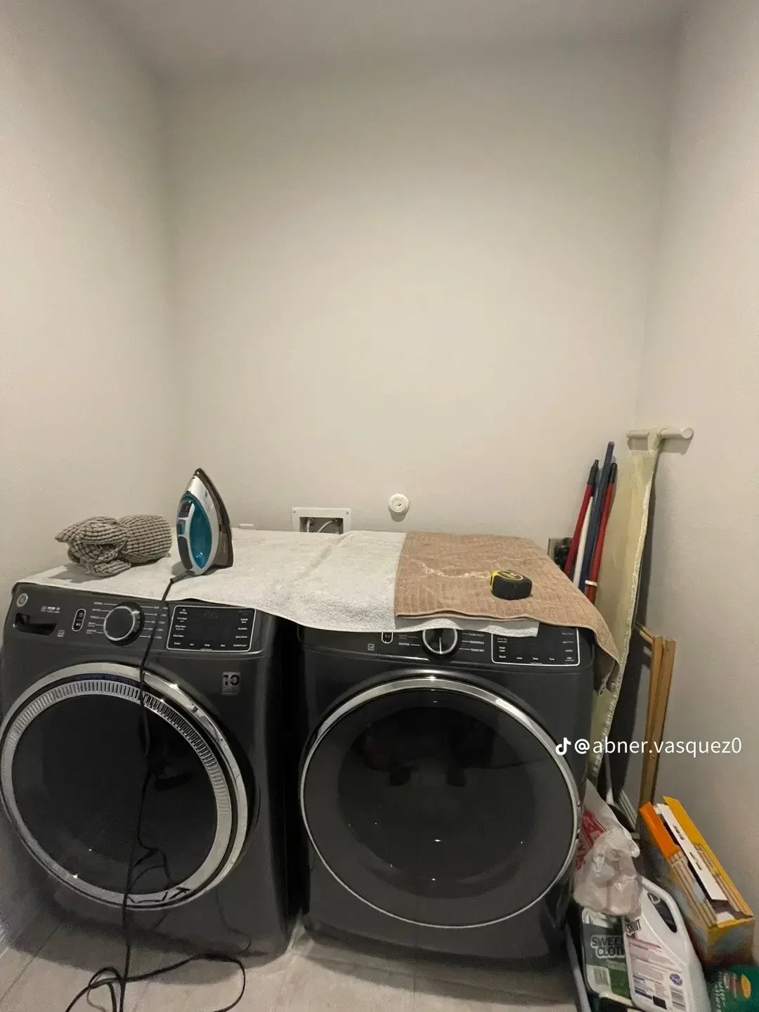 Two black front-load washers and dryers with white countertop and storage organization