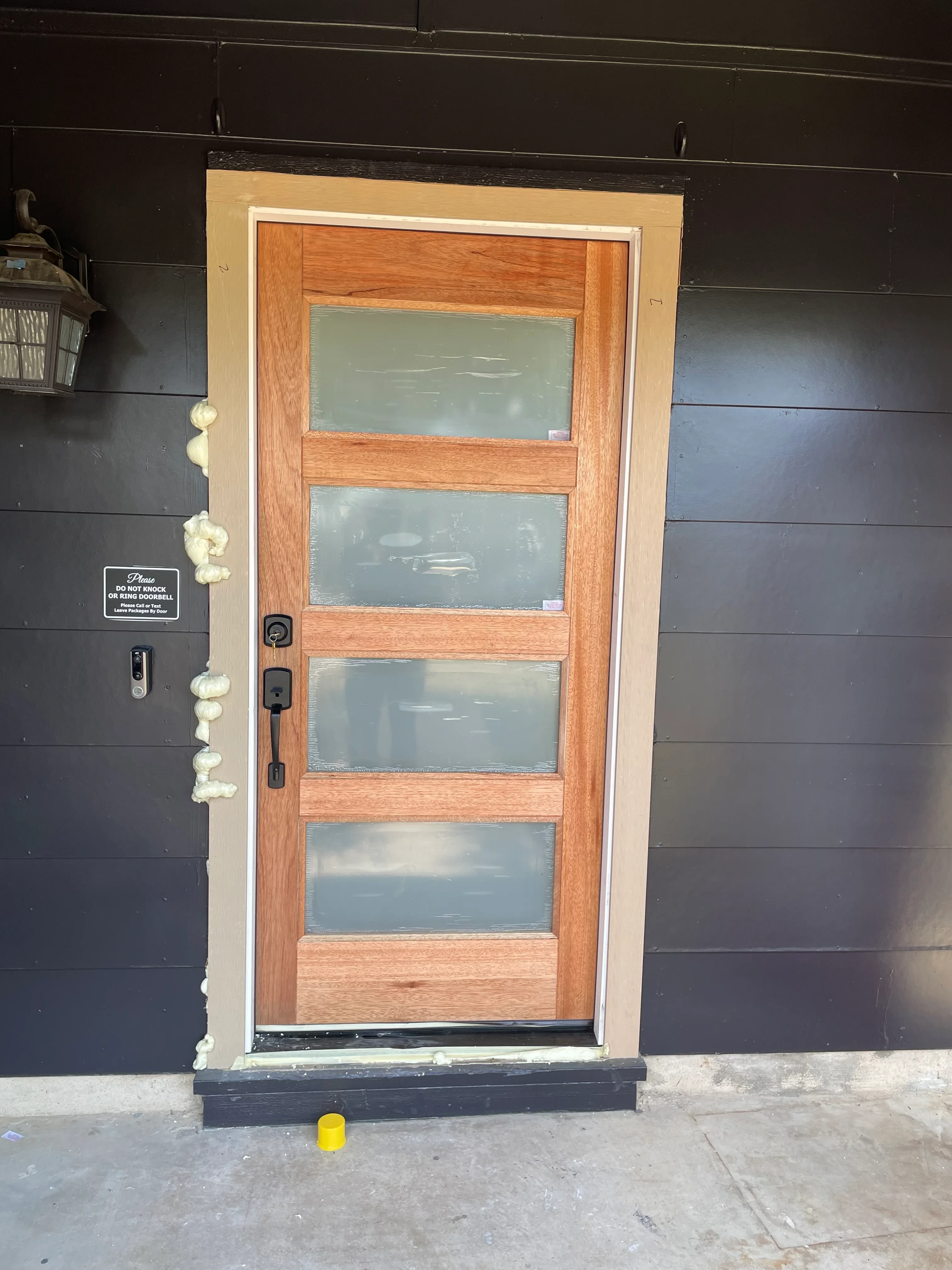 Four-pane wood window with frosted glass and oak frame installed in dark panel wall