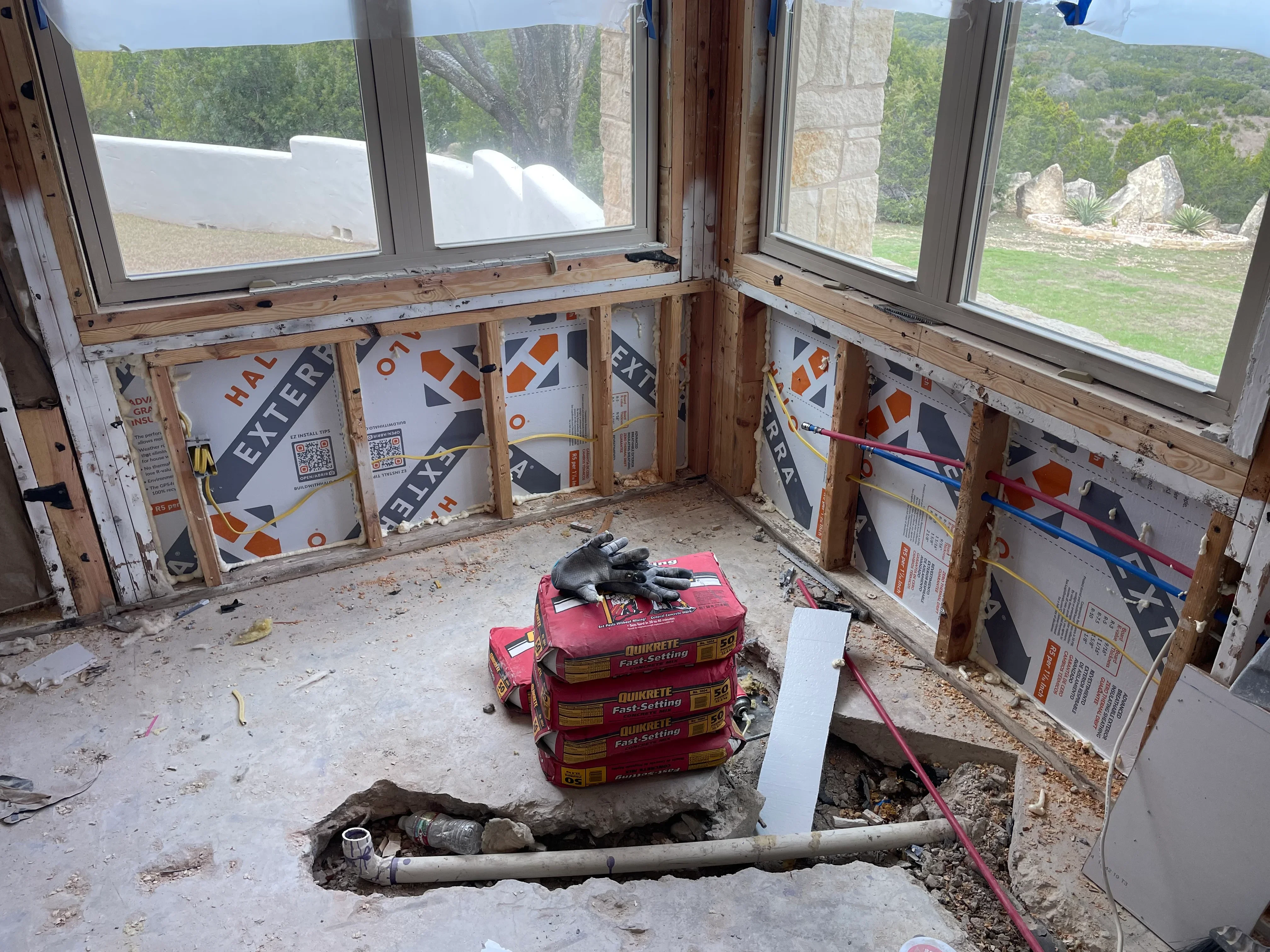 Multi-window installation with aluminum frames, wooden framing, and concrete foundation work in progress