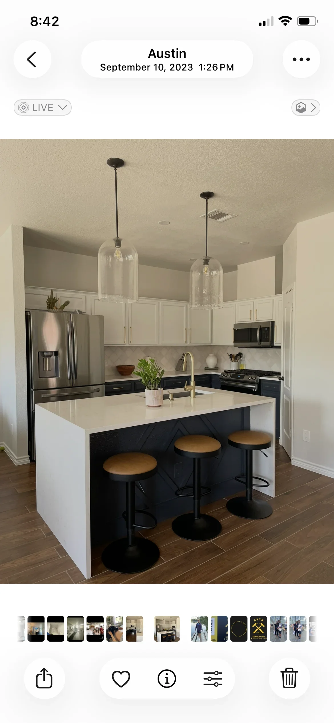 Modern kitchen with white cabinets, black island, quartz counters, and glass pendant lights
