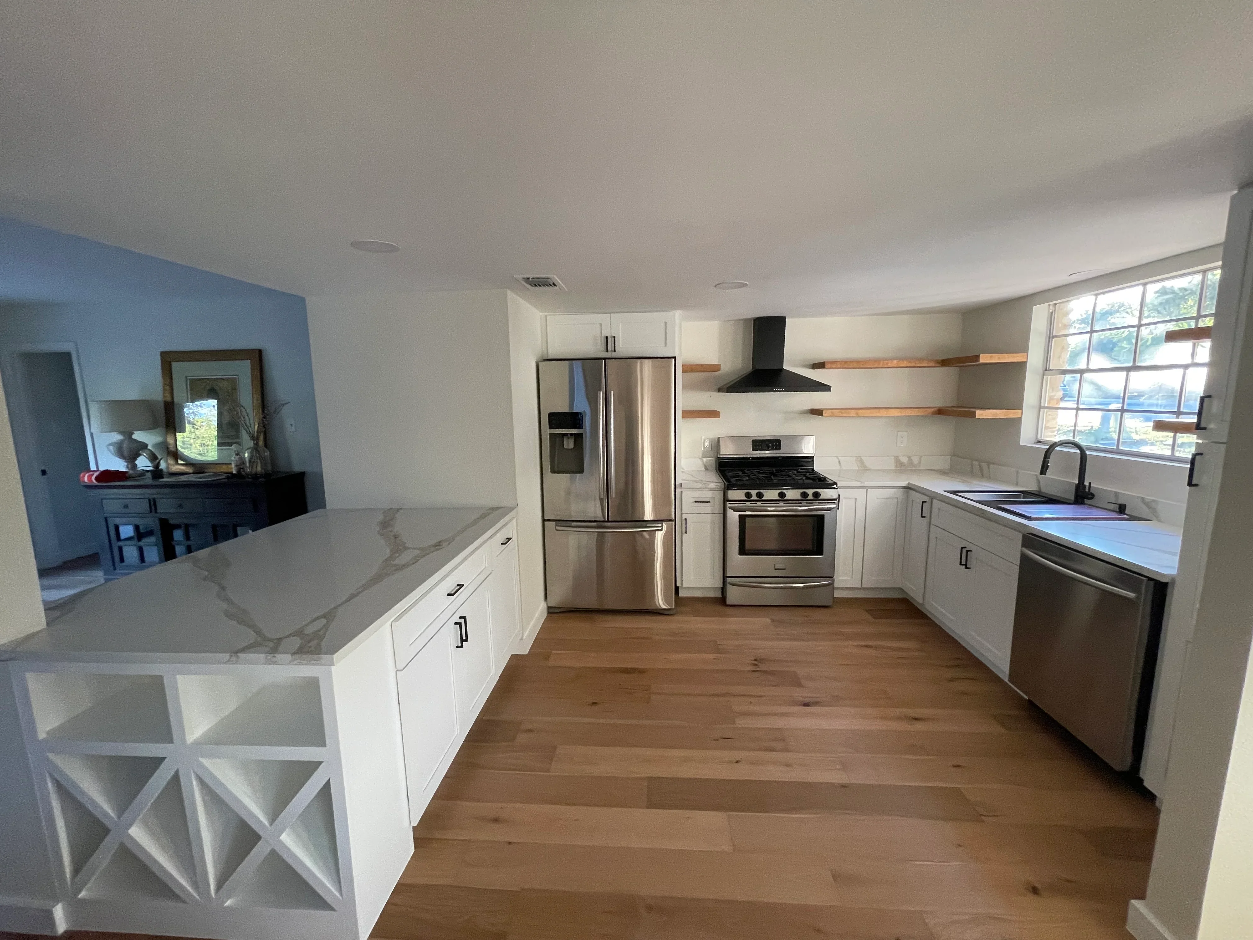 Modern kitchen with white cabinetry, stainless steel appliances, quartz counters, and hardwood flooring